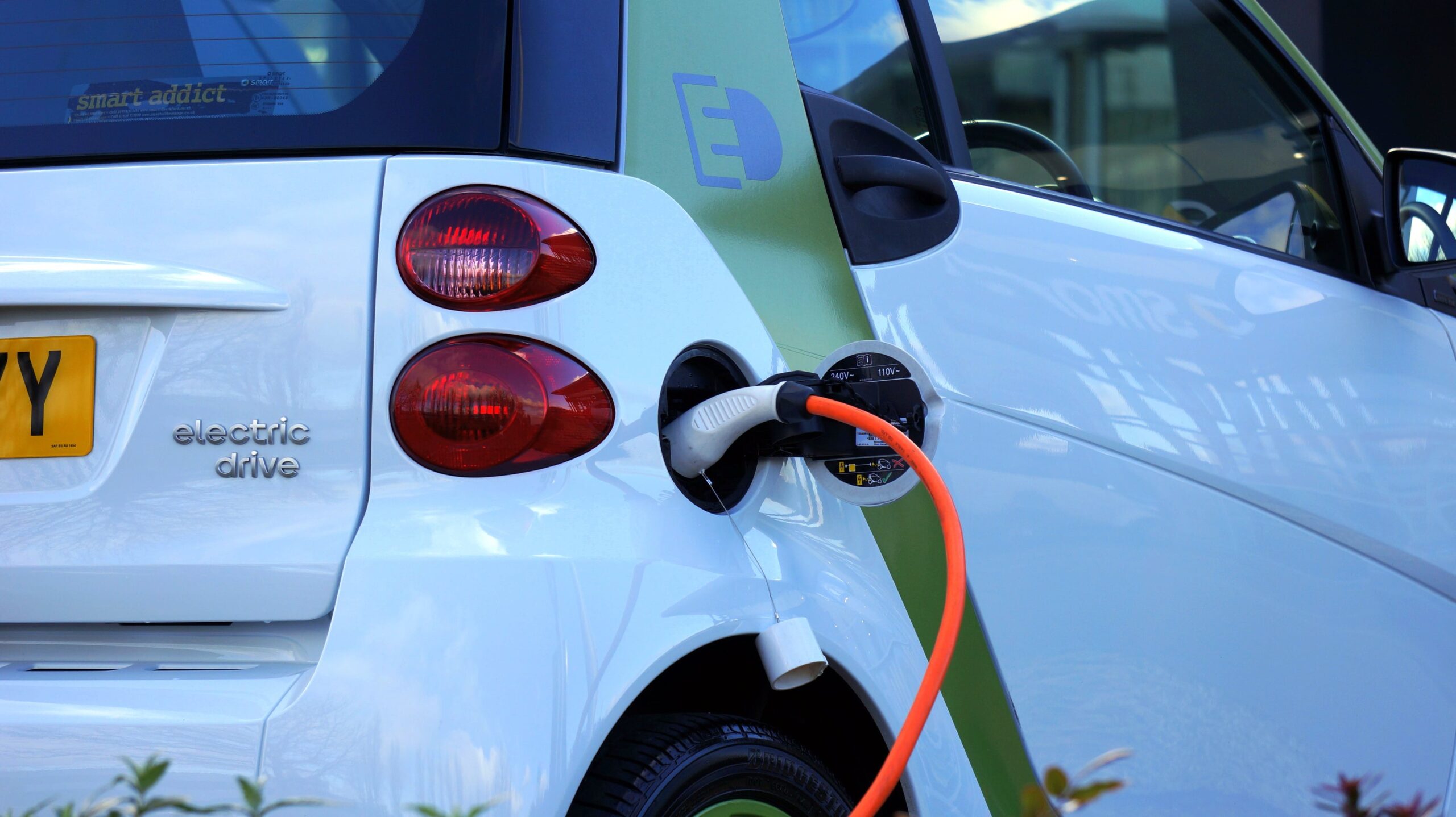 Carro elétrico branco e verde sendo carregado