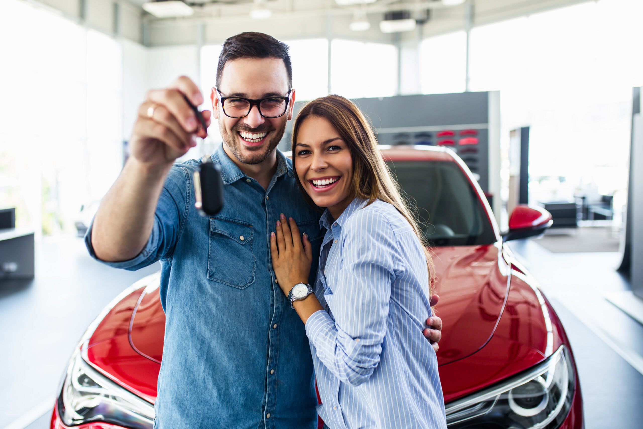 Casal sorrindo e segurando chave de carro