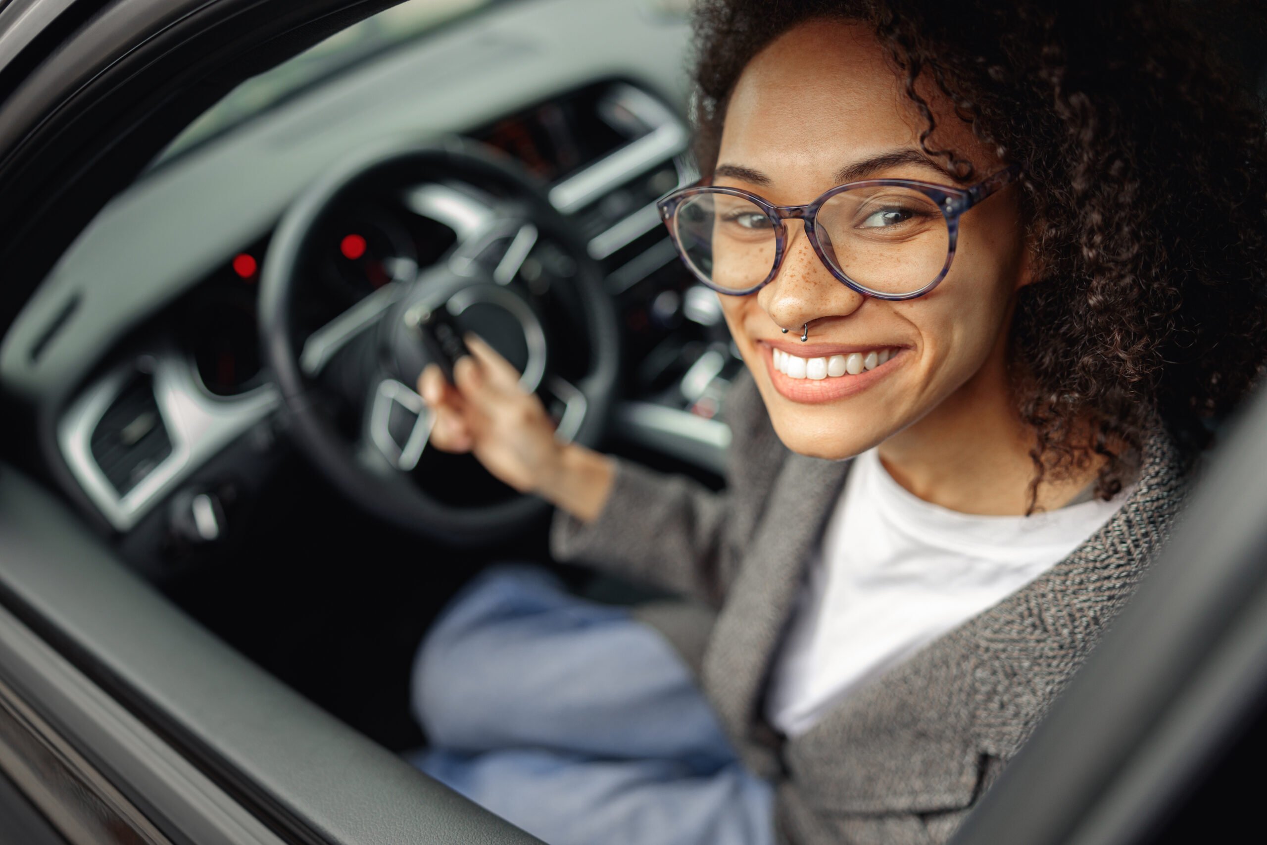 Mulher sorrindo no banco de motorista do carro