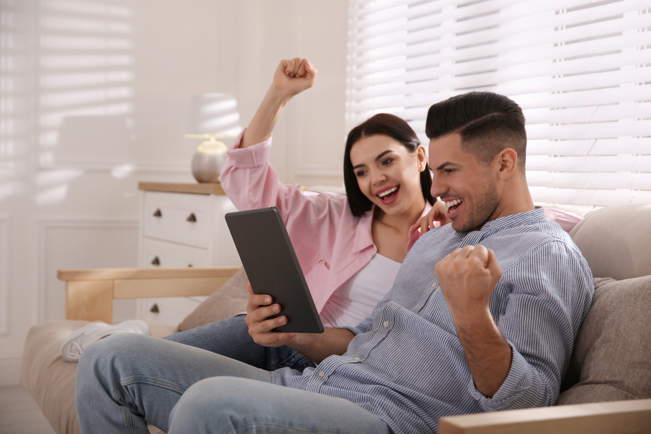 Casal olhando tablet e festejando